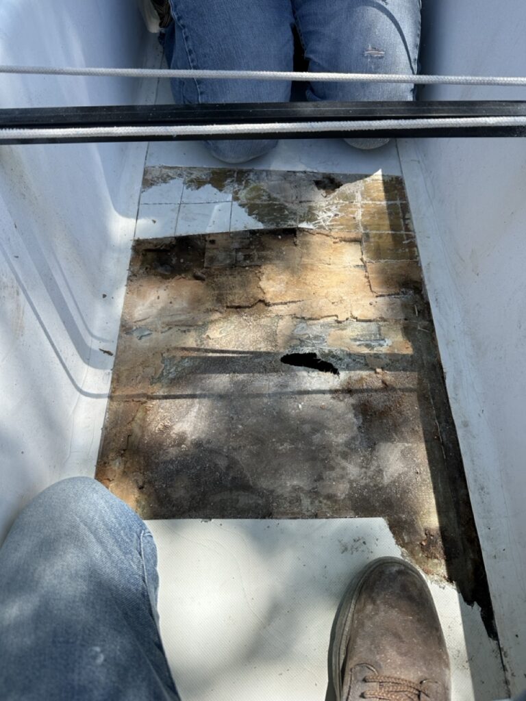 Close-up of wet, rotted balsa core exposed in the cockpit sole